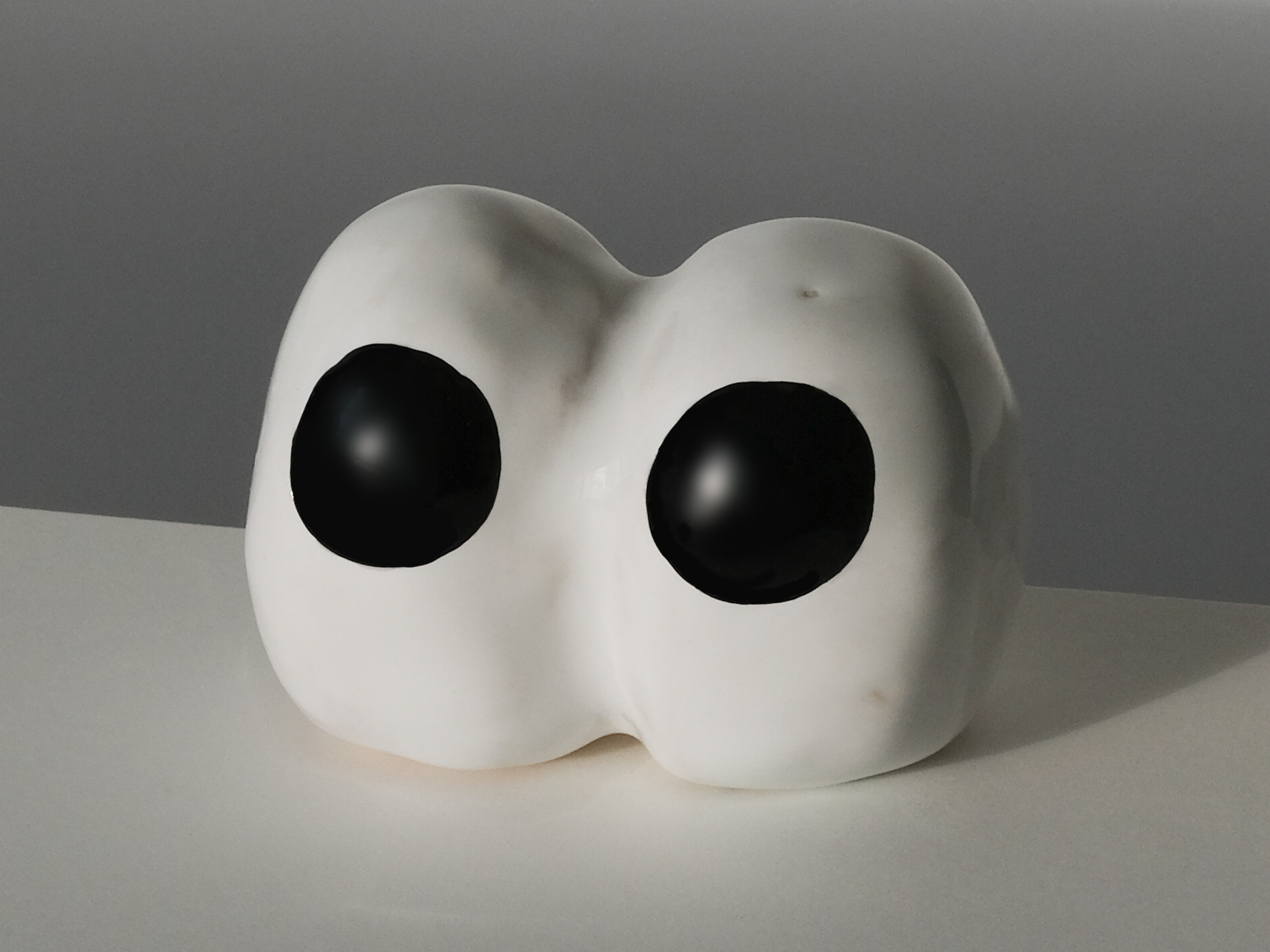A pair of eyes made from clay stadning on a white surface