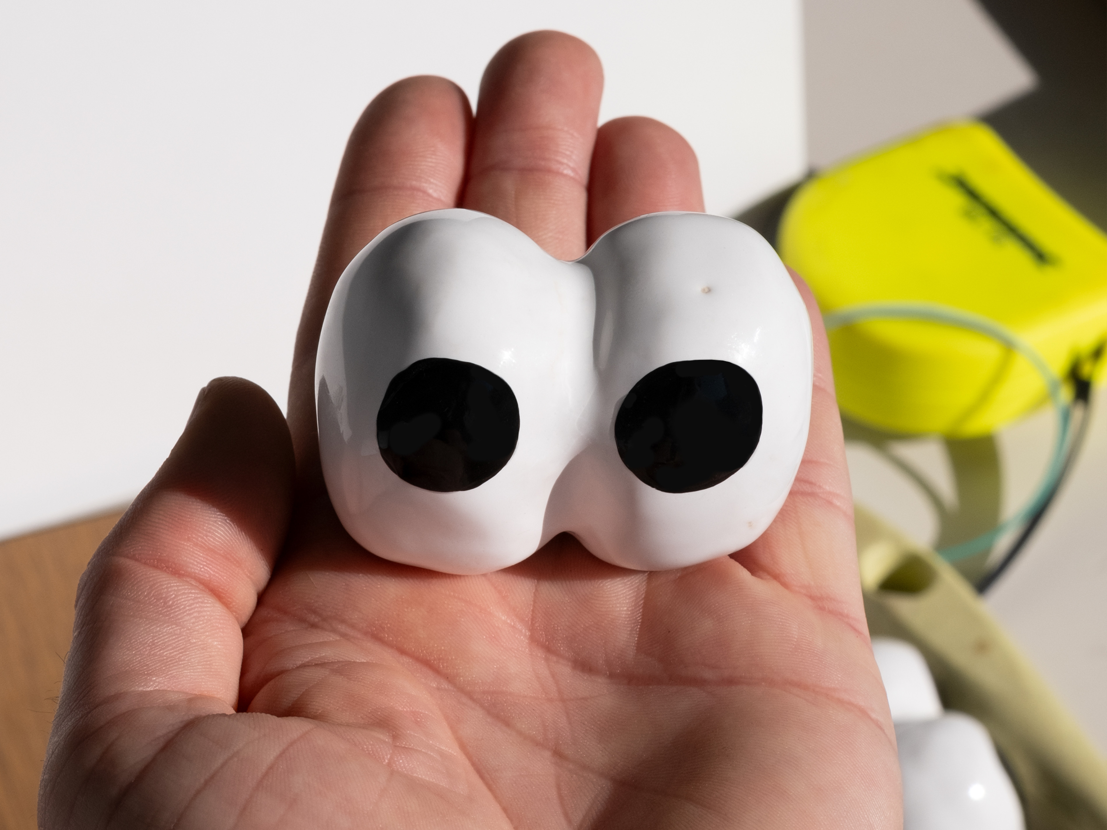 A hand holds a pair of ceramic eyes