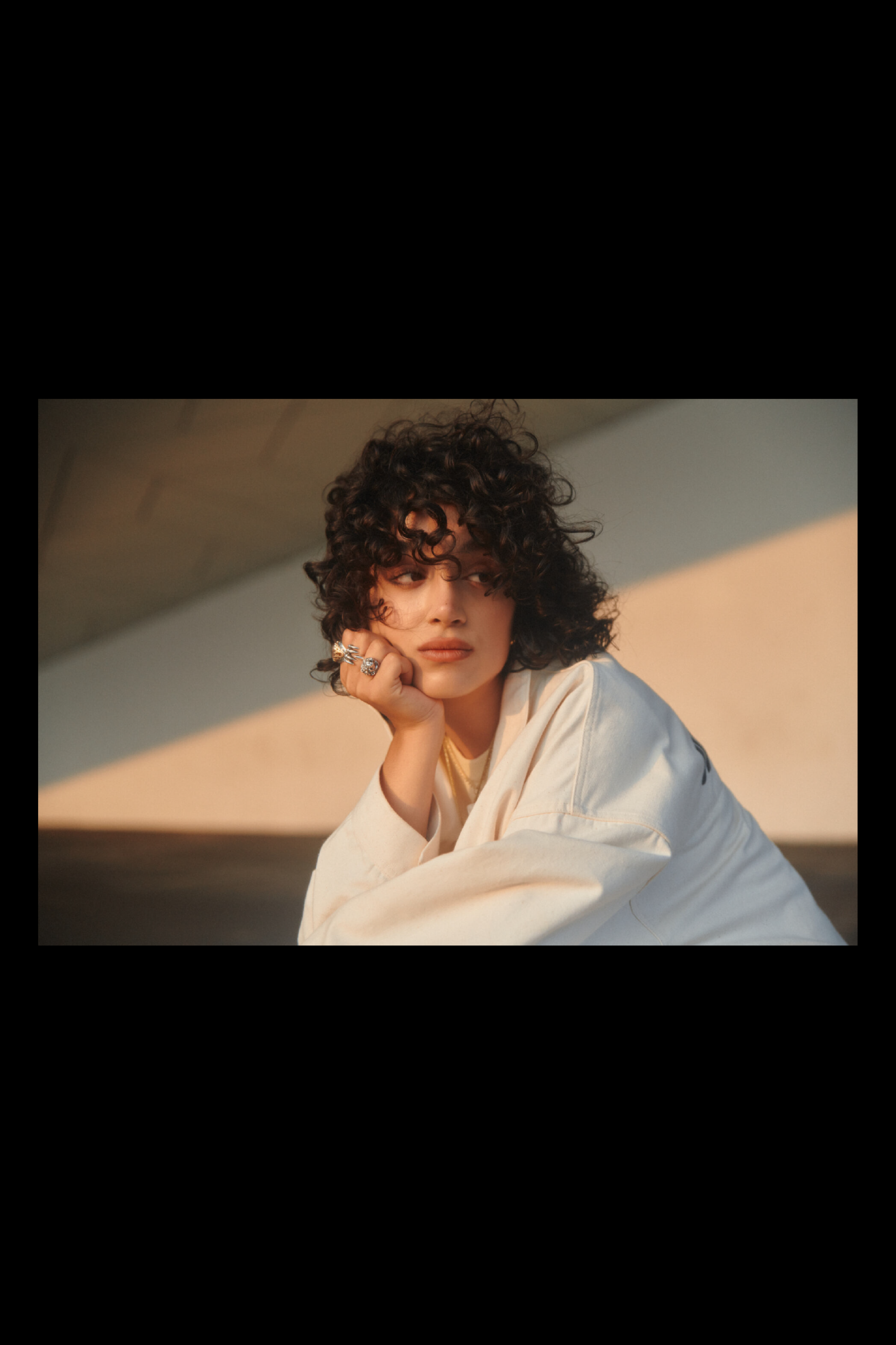 Photography of a young woman in warm sunlight with architectural elements in the back