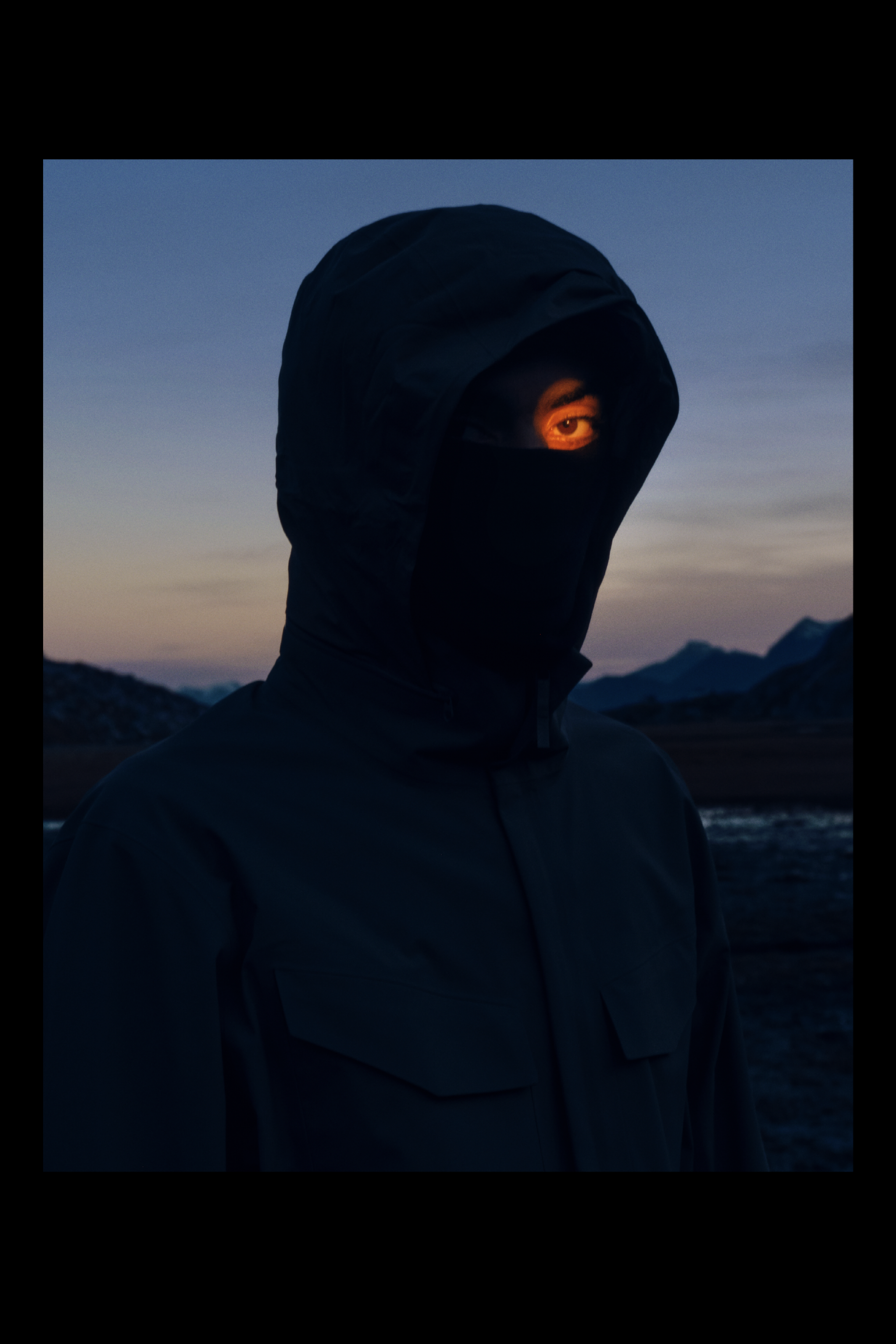 Photography of a dark dressed person in front of mountains